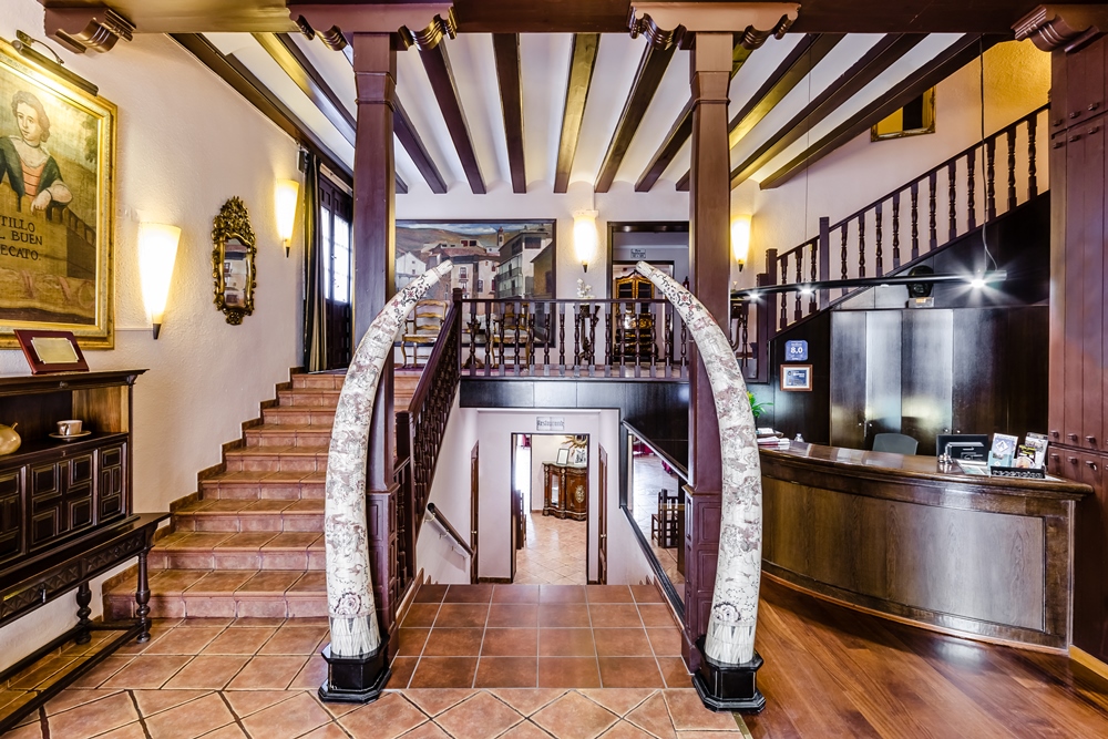 Vestíbulo del Hotel Albarracín con escaleras de madera y arcos centrales