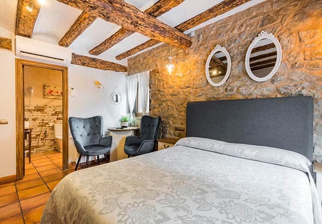 Habitación de la Posada del Rodeno con muro de piedra y vigas de madera