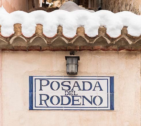 Rótulo cerámico de la Posada del Rodeno bajo un tejado nevado