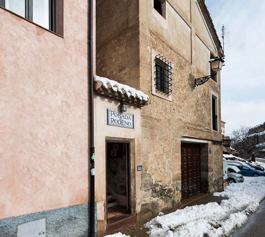 Fachada de piedra de la Posada del Rodeno y su acceso entre la nieve