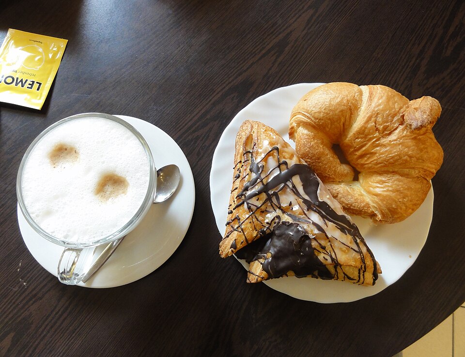Café con leche acompañado de cruasán y una pieza de bollería caliente