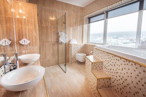 Baño con lavabos, ducha y bañera en Hotel Hafnia