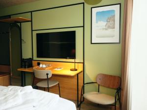 Dormitorio con escritorio y televisor en Hotel Vagar