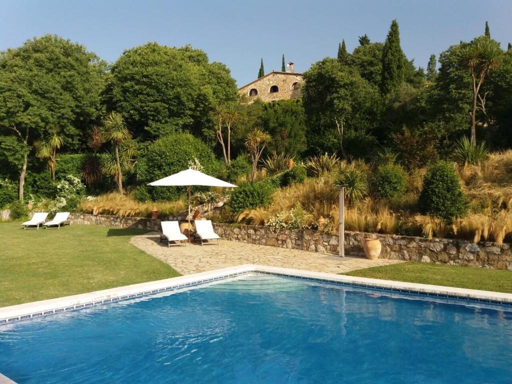 Piscina en un patio con sillas y sombrilla en Can Serola, en Sales de Llierca