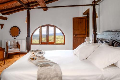 Dormitorio con cama blanca grande y ventana en Can Serola, en Sales de Llierca