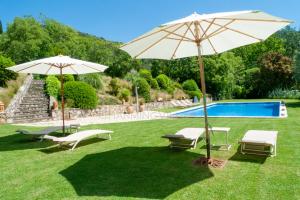 Patio con dos sombrillas y piscina en Can Serola, en Sales de Llierca