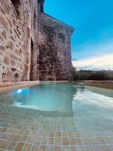 Piscina frente a un edificio de ladrillo en Hotel Cal Sastre, en Santa Pau