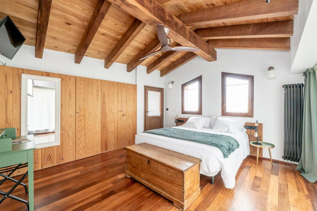 Dormitorio con cama y techos de madera en Hotel Mas la Ferreria, en La Vall de Bianya