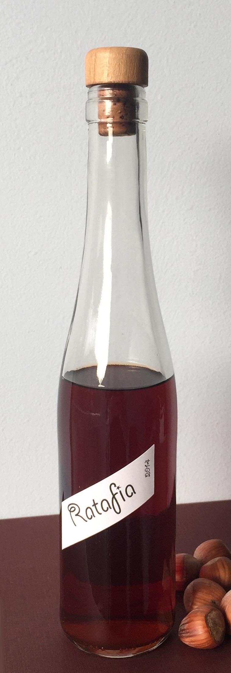 Botella de ratafía casera junto a unas avellanas