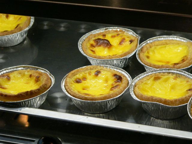 Seis pastéis de nata recién horneados sobre una mesa