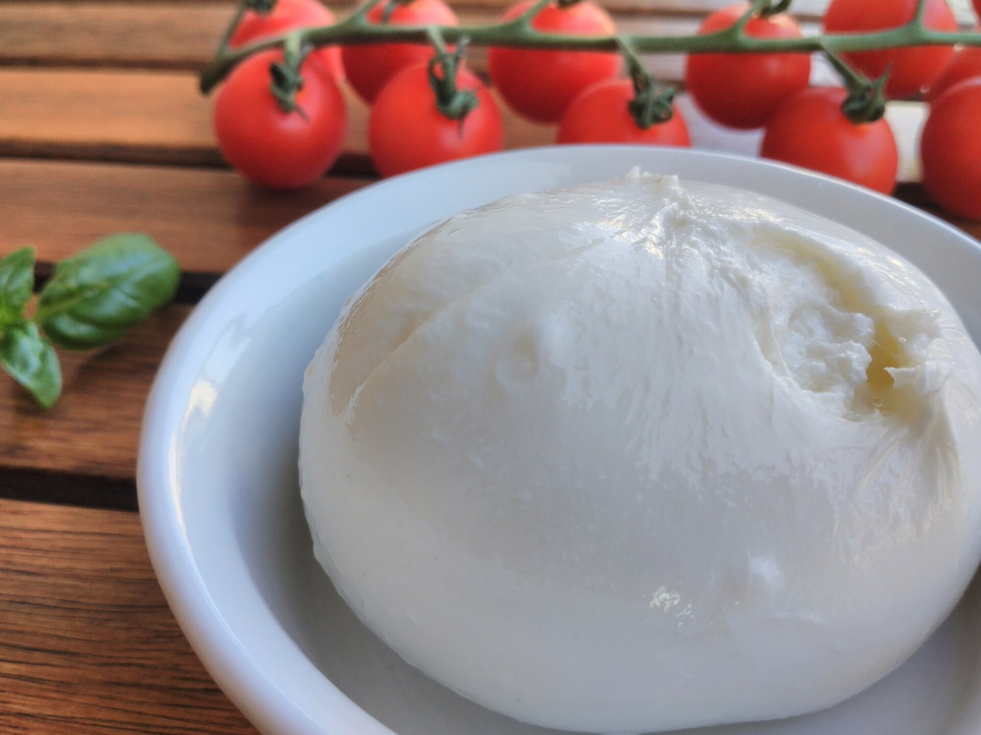 Burrata fresca blanca servida en un plato junto a tomates